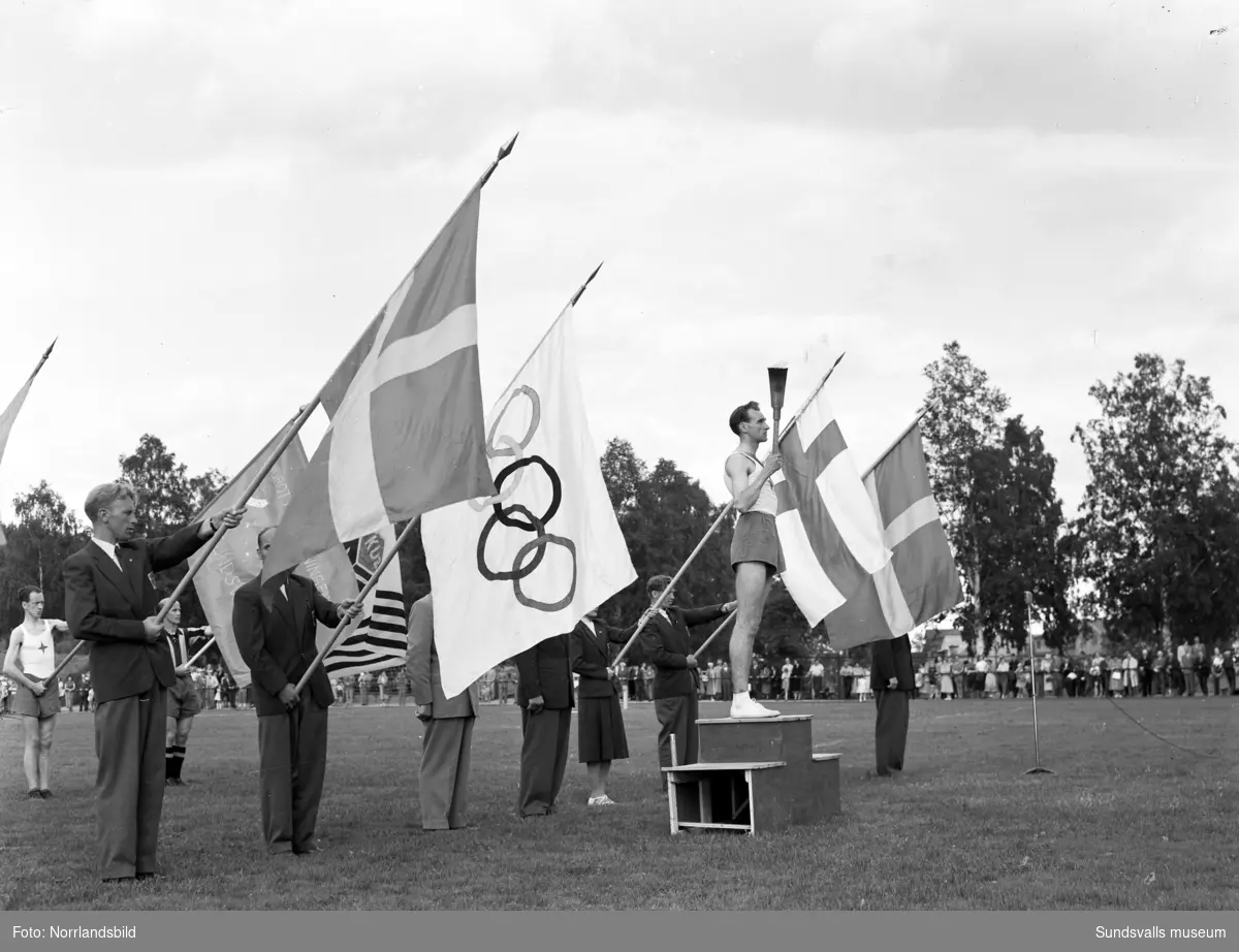 Den olympiska elden passerar Sundsvall inför sommarspelen i Helsingfors 1952 med högtidlig stafettväxling i Idrottsparken. In på arenan förs facklan av IFK-löparen Eric Nilsson, som är uttagen till Olympiaden på 3000 meter hinder. Därefter tar SAIK-brottaren och OS-silvermedaljören från 1936, John Nyman över för att påbörja facklans färd vidare mot Härnösand och Kramfors.