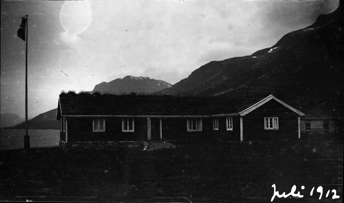 Feriebilde. Turisthytte ved et  fjellvann fotografert. Bildet er tatt i juli, 
1912

Fotoarkivet etter Gunnar Knudsen.