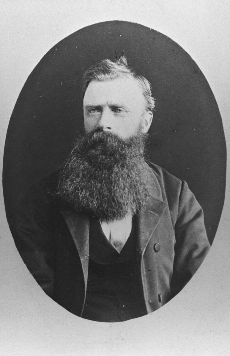 Halvkropsportrett av en eldre mann med lang mørk skjegg og bart. Bildet er kopiert i ovalform