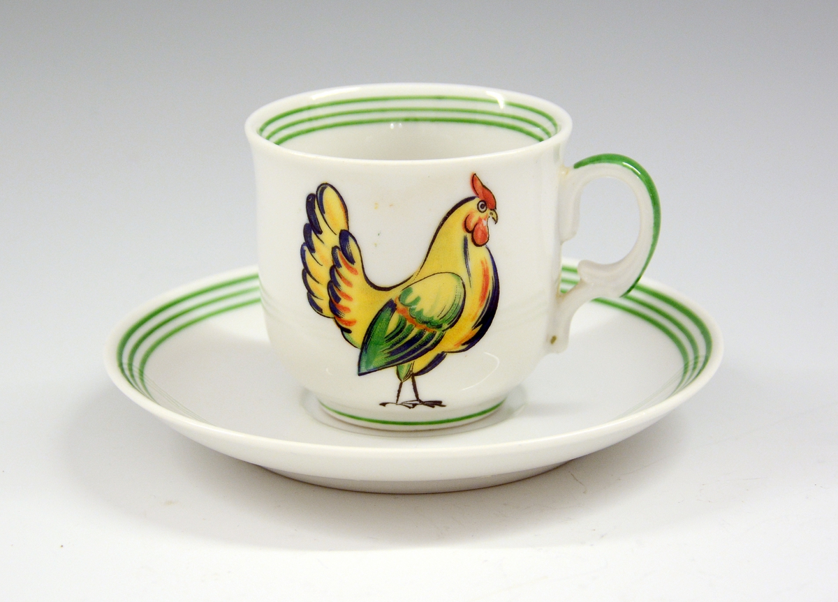 Kaffeskål i porselen til dukkeservise. Hvit glasur. Grønn strek.
Modell 1460.
Dekor "Hønen Petrine 1".