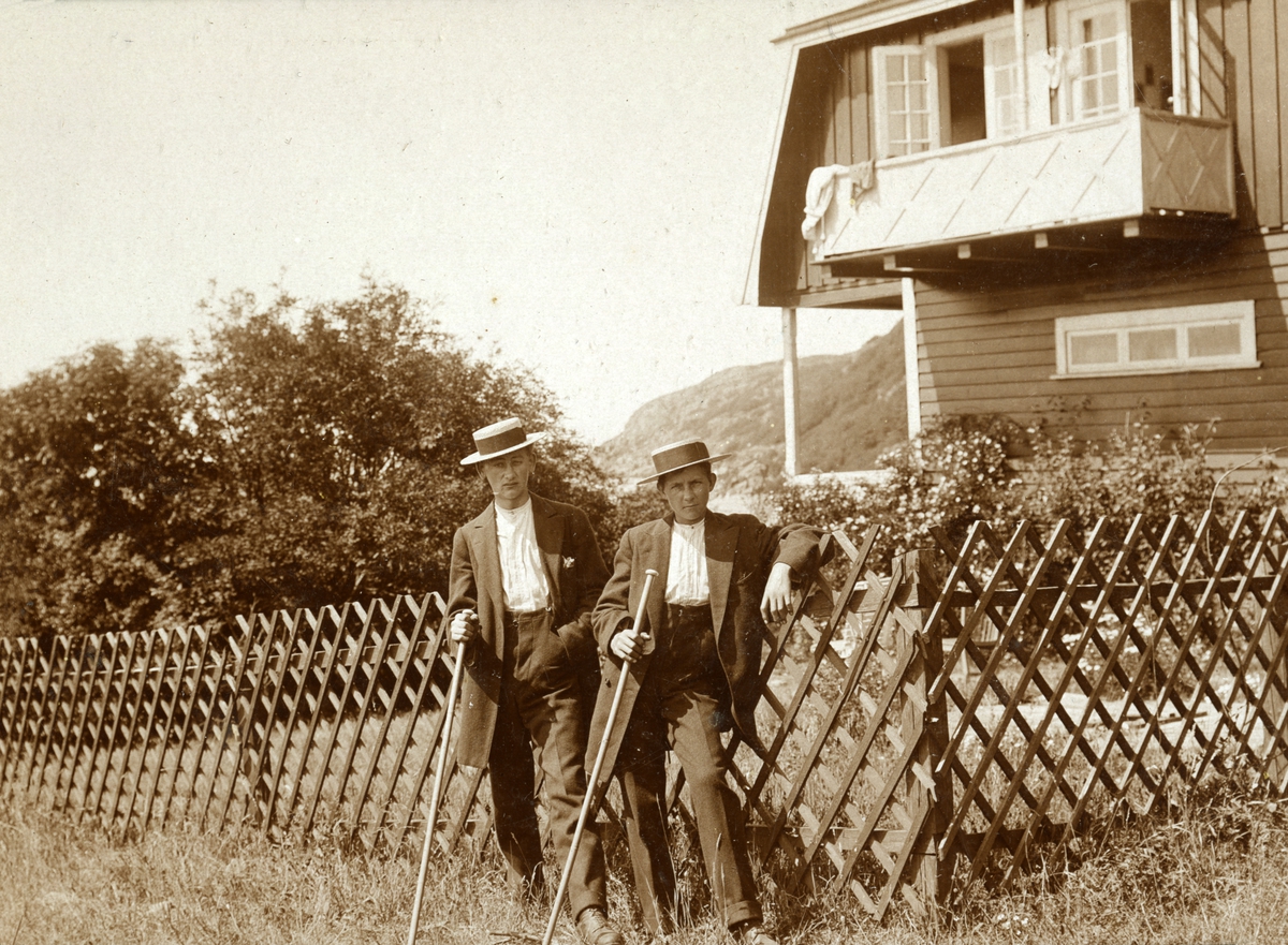 Civilklädda herrar poserar framför ett hus.