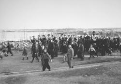 8. mai 1945 i Vadsø. En gruppe barn og voksne går i tog. Et 