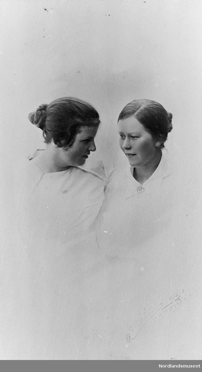 Fagfoto av 2 kvinner begge har lyse bluser og oppsatt hår.