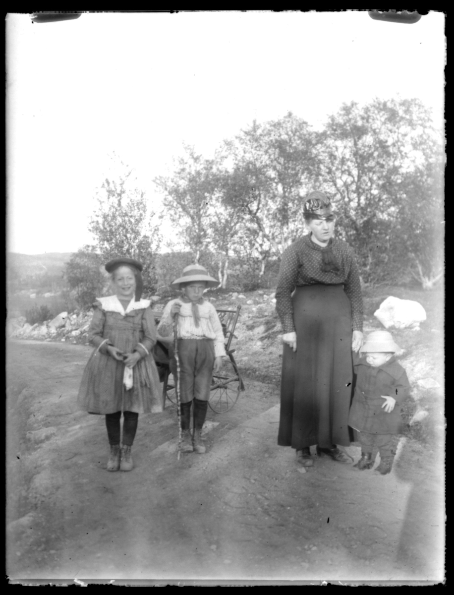 Gruppebilde av fru Grasmo og tre av barna hennes, dem står på en vei.