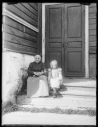 Boris Gleb, en eldre kvinne og ei ung jente sitter på trappa