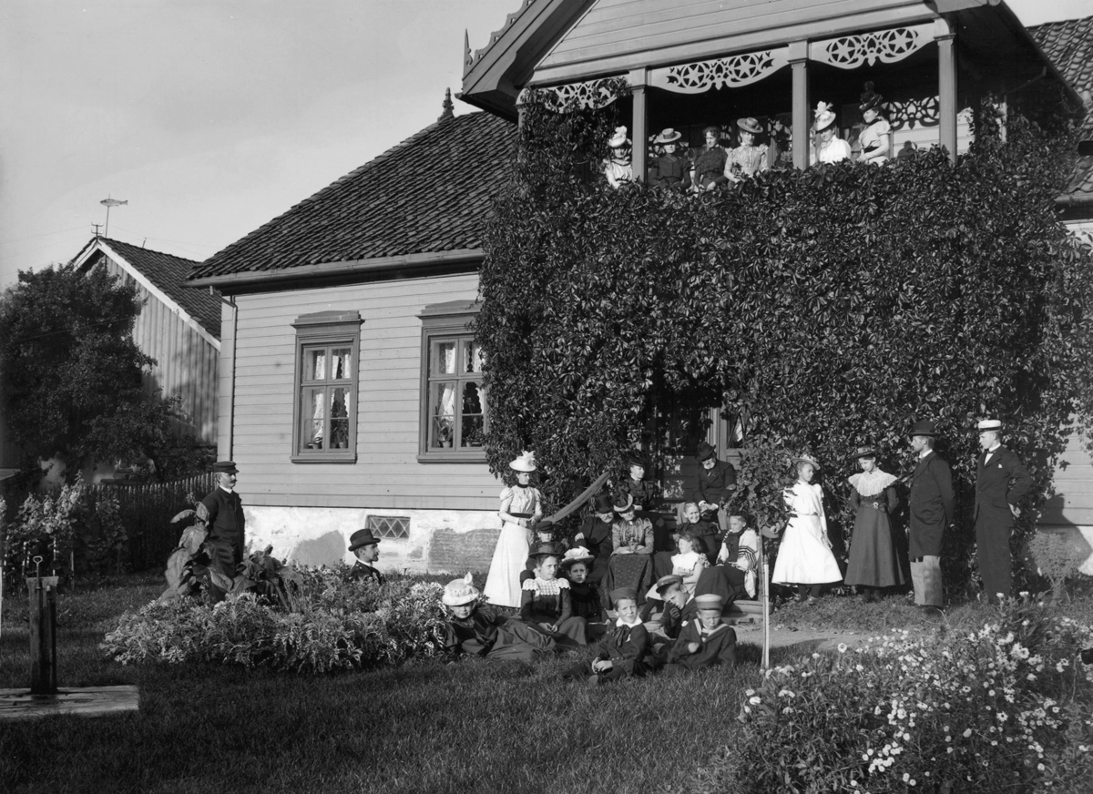 Fotoarkivet etter Gunnar Knudsen. Mennesker i hagen foran empirehus.