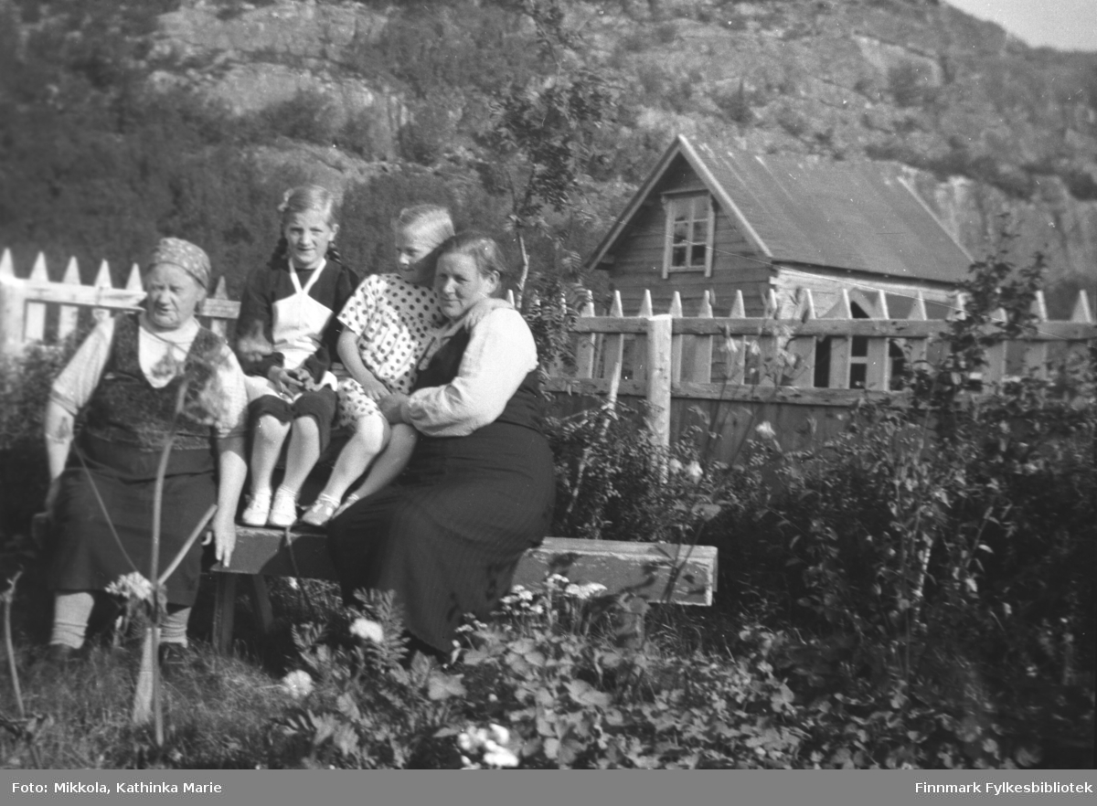 Hagebenken på Mikkelsnes. Fra venstre: Ida Angel, Astrid og Herlaug Mikkola og en ukjent kvinne på besøk fra Vadsø. I bakgrunnen ser vi melkebua på gården