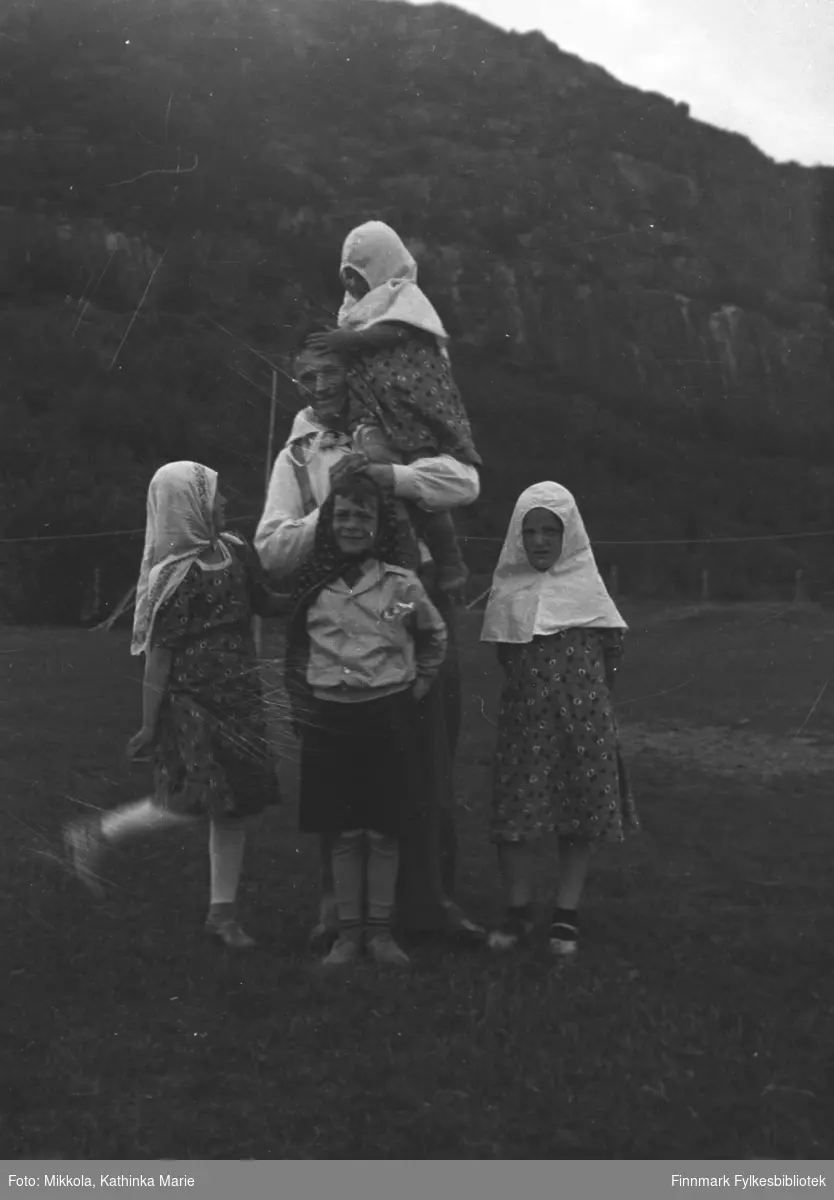 Barn med mygghetter på jordet til Mikkelsnes. Jentene fra venstre: Gudrun, Herlaug og Astrid Mikkola. Mannen som holder Herlaug, og gutten som står i front er ukjente