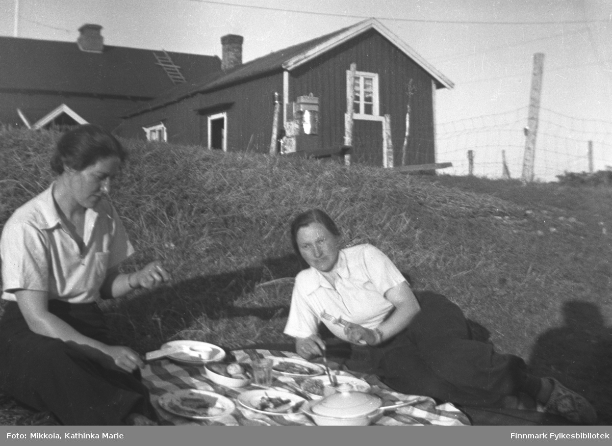 Middag utendørs, rett i nærheten av våningshuset på gården Mikkelsnes. Kvinnen til venstre: Stine Olsen, søster av Kathinka Mikkola. Kvinnen til høyre vet vi ikke navnet til, men hun var venninne av Stine