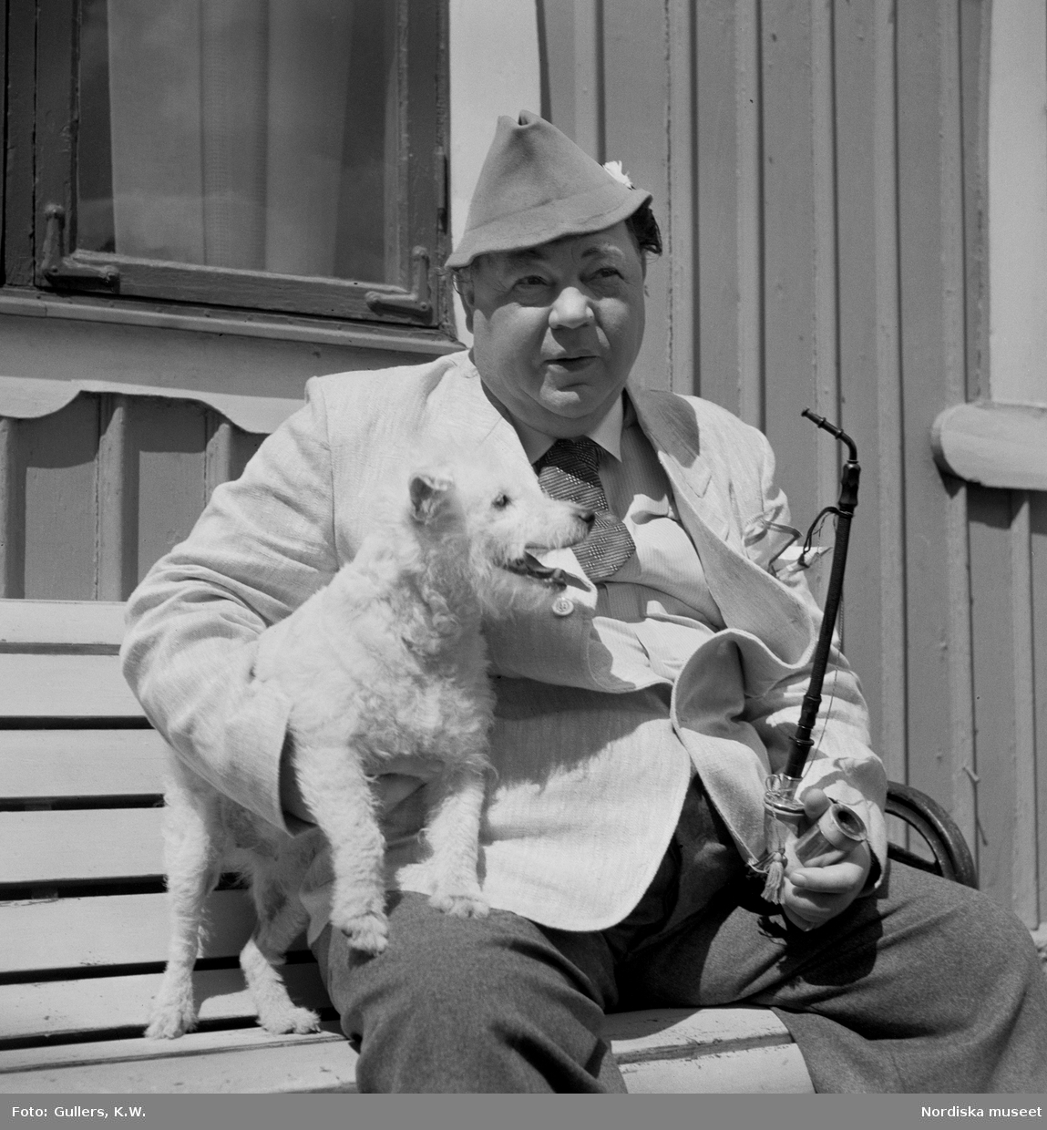 Skådespelaren Edvard Persson med pipa och hund. Bilden troligen tagen i samband med inspelningen av filmen Kalle på Spången i regi av Emil A. Lingheim 1939.