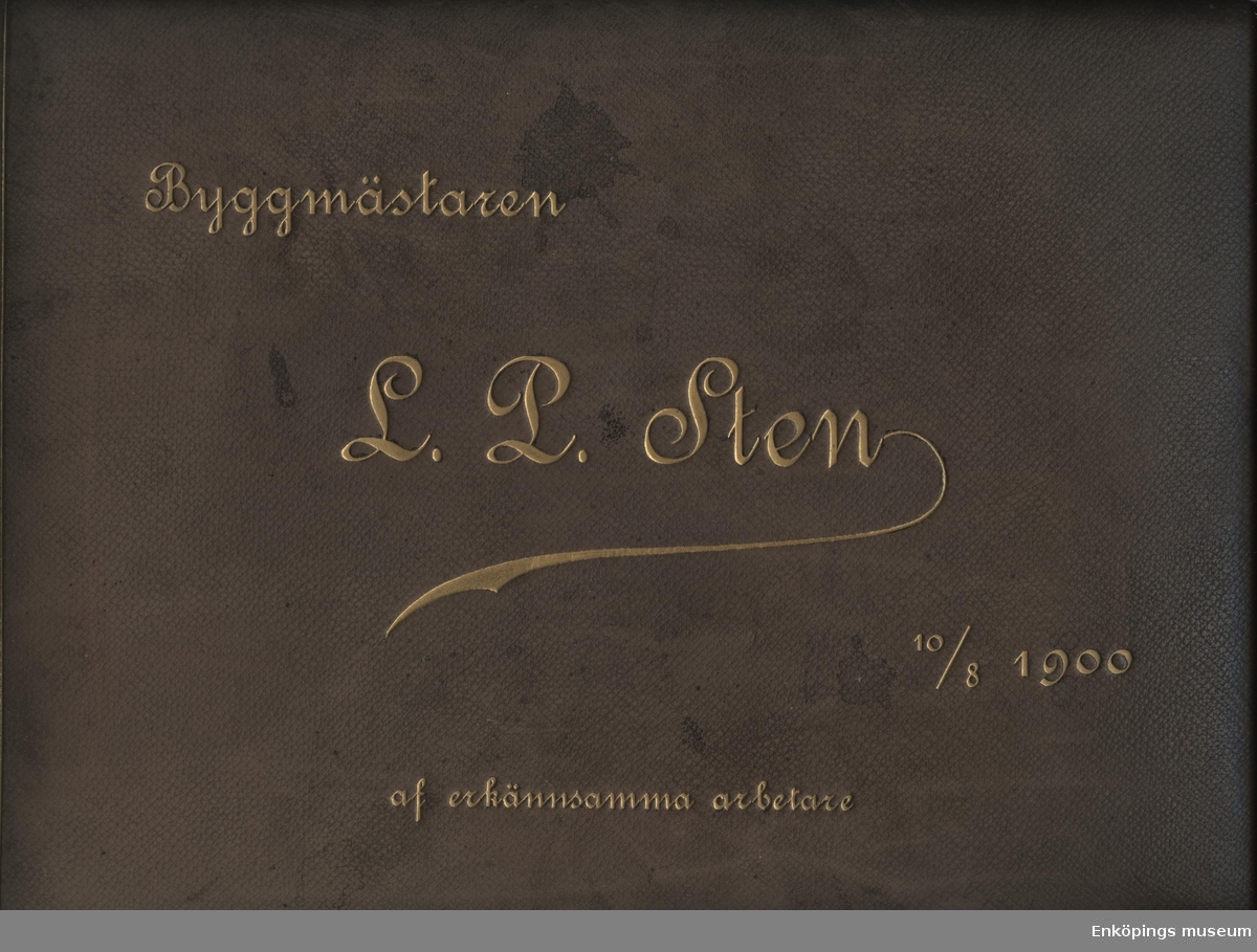 Inplastat brunt fotoalbum i skinn. På framsidan står det "Byggmästaren L. P. Sten, 10/8 1900, af erkännsamma arbetare".