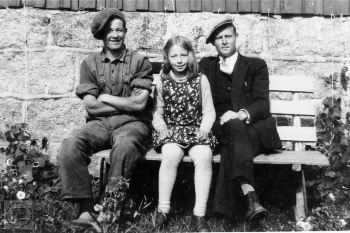 Med lua på snei, tre på en benk.
Ny info - okt. 2022: 
Mannen til venstre er Otto E.Ljosland (onkel til Ella)