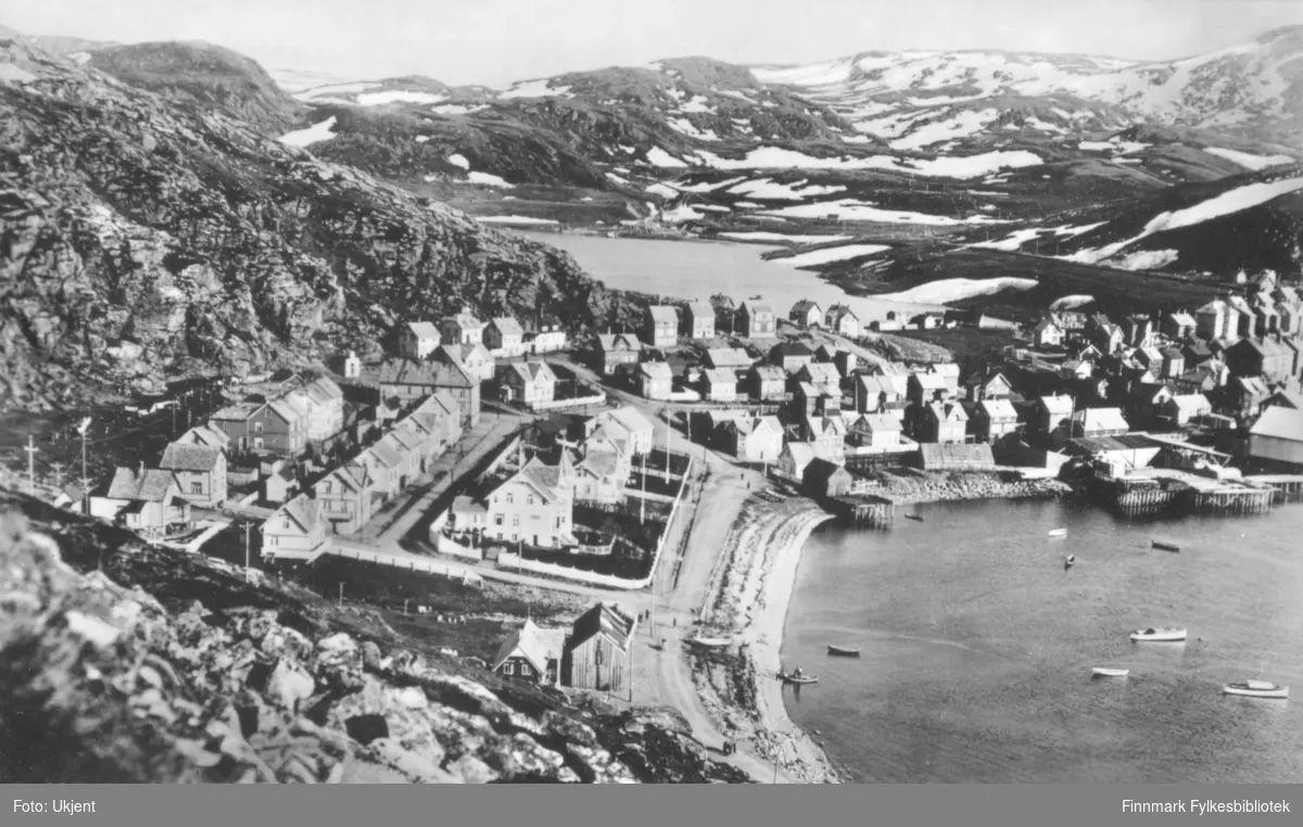 Et postkort med Hammerfest som motiv. 'Mollen, Hammerfest' er trykket på postkortet. På bilde kan man se flere hus og gater. Enkelte av husene har store hager. Langs fjæra kan man se robåter og kaier. Det er blitt satt opp strømlinjer rundt om kring. I bakgrunnen kan man se fjell.