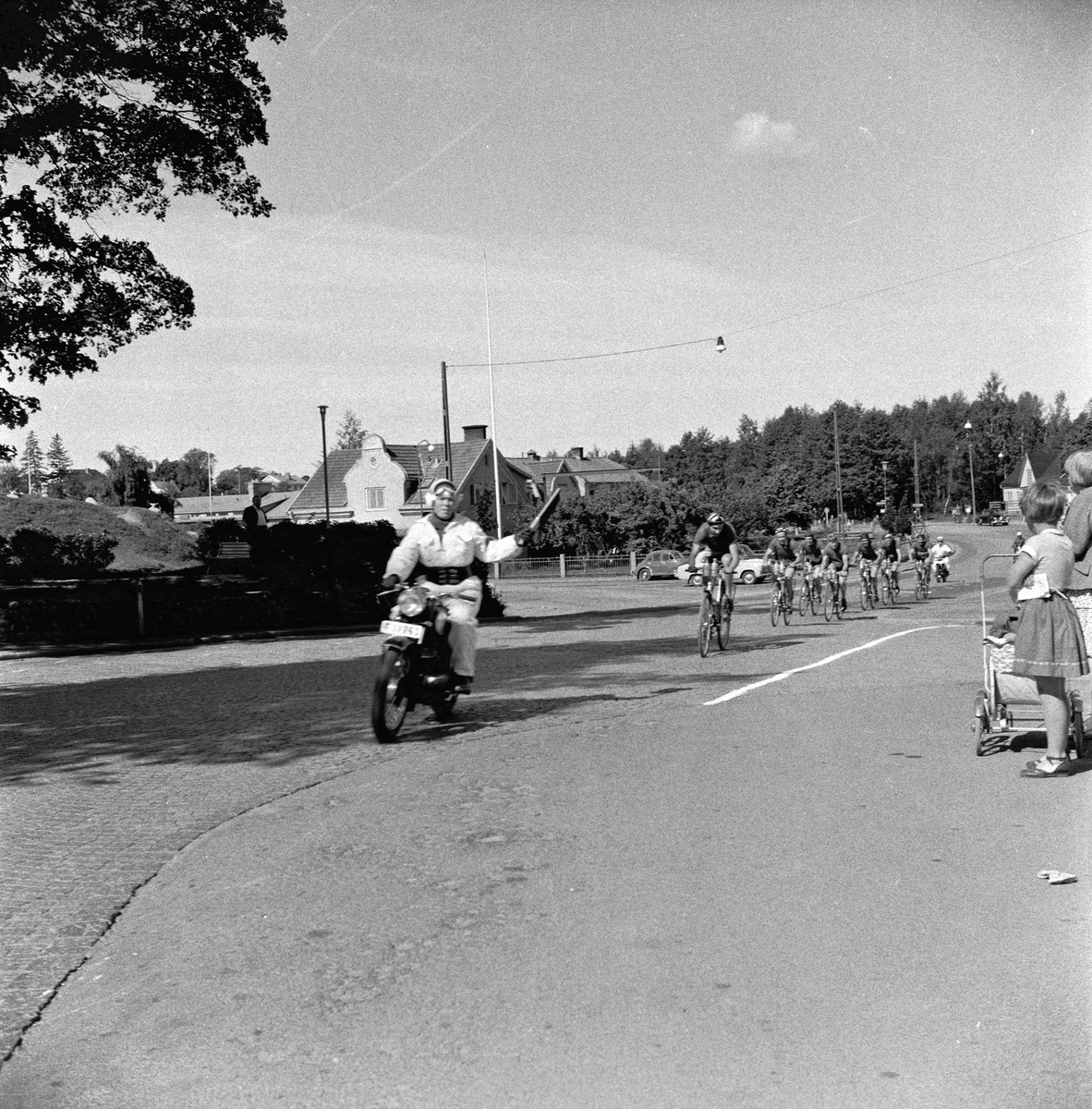 Tävlingscyklister passerar gamla infarten till Huskvarna vid Shellmacken innan bron byggdes.