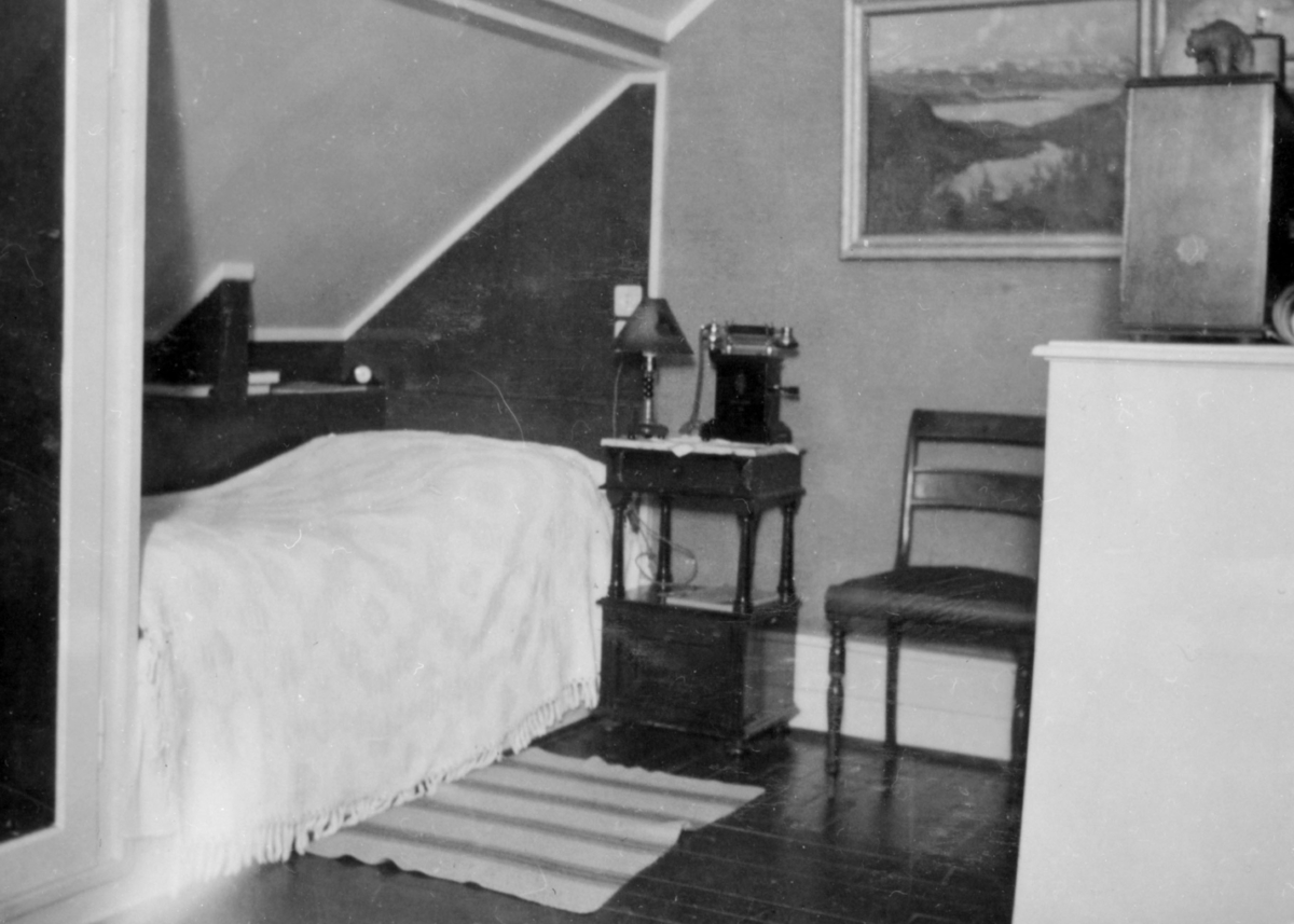 Bilder fra Hartvig Skuteruds album, utlånt av Anne Hulda Skuterud, Båtsfjord. Hartvig Skuterud var assistentlege i vadsø 1934-36. Alle bildene er fra denne perioden. Et interiørbilde fra Skuteruds hybel i ingeniør Matzows hus i Vadsø. Soverommet med nattbord og telefon.