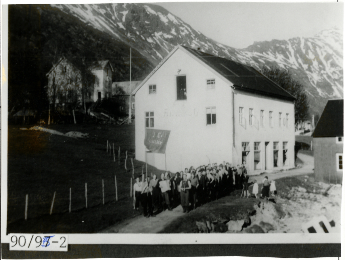 Bildet viser et 17.mai tog med handsskole-elevene i Sigerfjord 1944. Her står elevene utenfor handelsskolen.