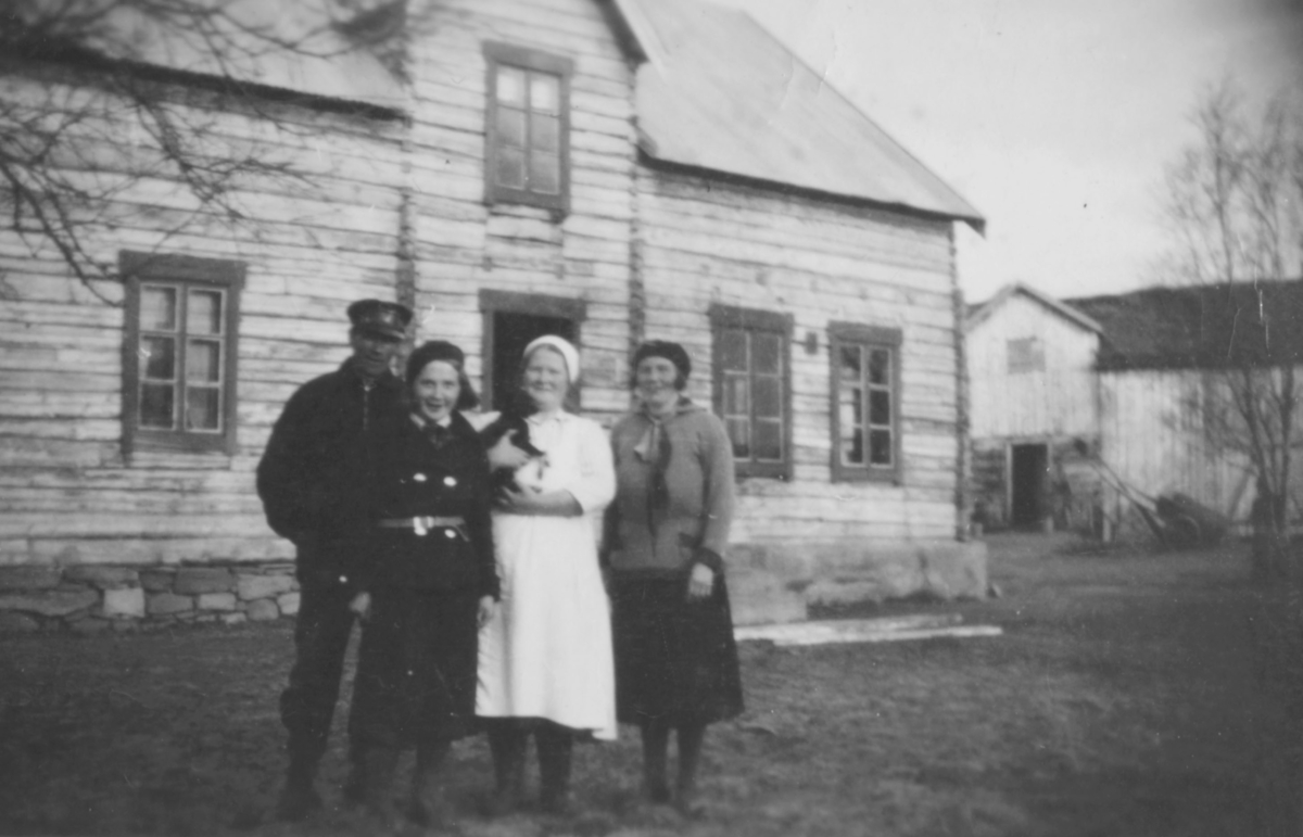 "Fra venstre: Alfred Aronsen, ukjent, Aina Marie Aronsen og ukjent foran bolighuset. Til høyre bak ser man ett av de to vinduene i klasserommet på Luftjok skole som det ble kalt på den tiden."