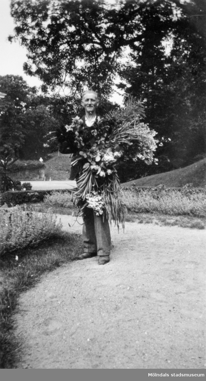 Charles Gunnehed (född Johansson) bär ett fång med blommor, Gunnebo slottspark 1930-tal. CG arbetade på Gunnebo som trädgårdsmästare och alltiallo. Även hustrun Sara (född Sjöstrand) arbetade som kokerska på Gunnebo.