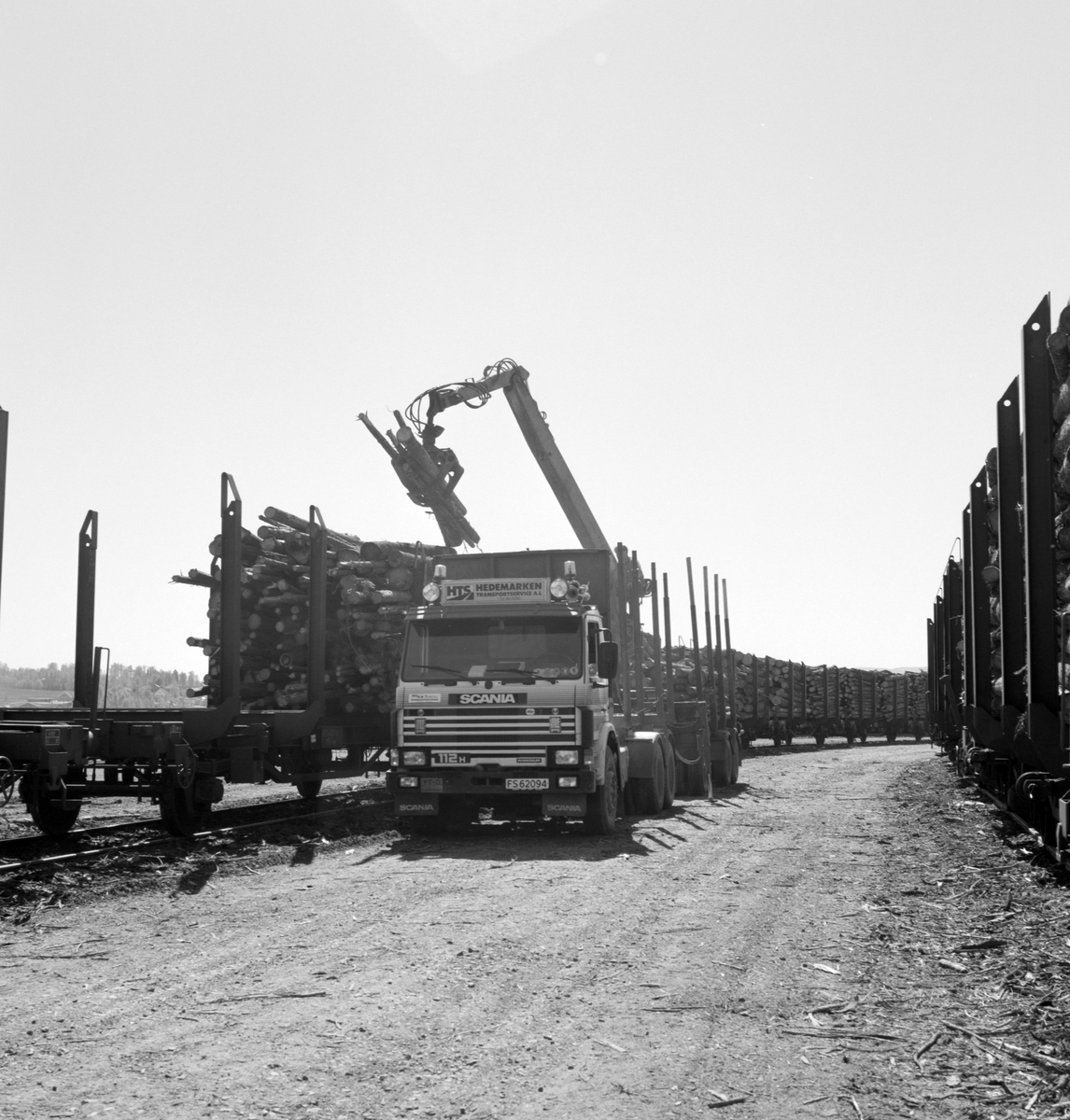 Åkersvika, Hamar. Tømmerterminalen, Scania tømmerbil FS-62094, Hedemarken Transportservice AL, opplasting av tømmer på jernbanevogn.