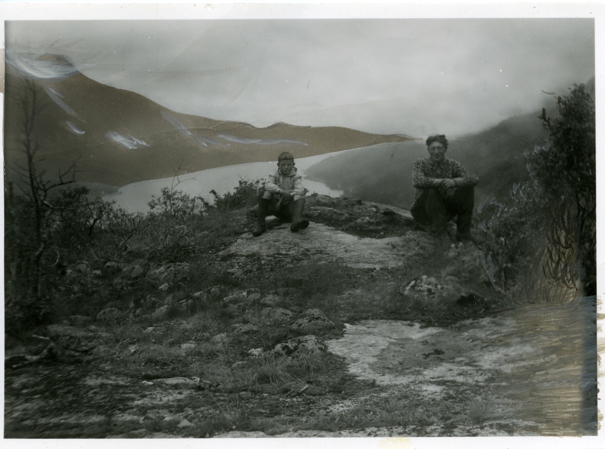 En gutt og en mann sitter foran utsikten over Vangsmjøsa.
