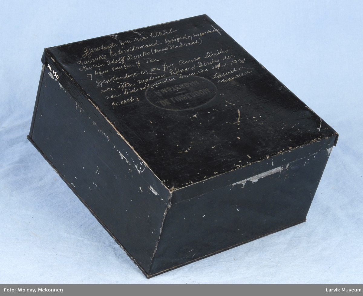 Kubeformet boks med lokk og skrift på lokket.
