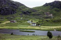 Gårdstun på Saupstad, med fjell og tunnell i bakgrunnen.