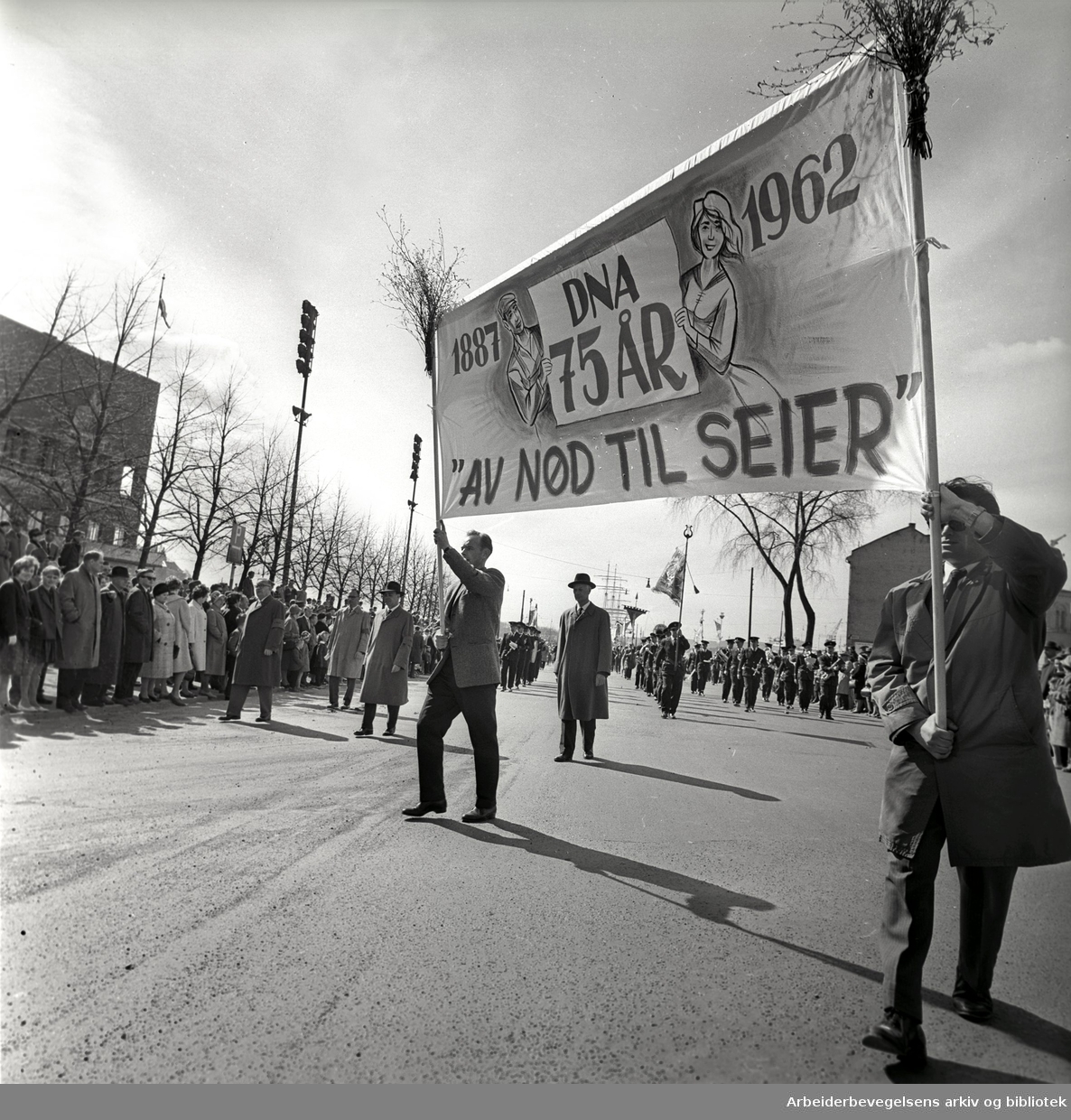 1. mai 1962 i Oslo.Demonstrasjonstoget.Parole: DNA 75 år.1887 - 1962."Av nød til seier".Bak ses Einar Gerhardsen