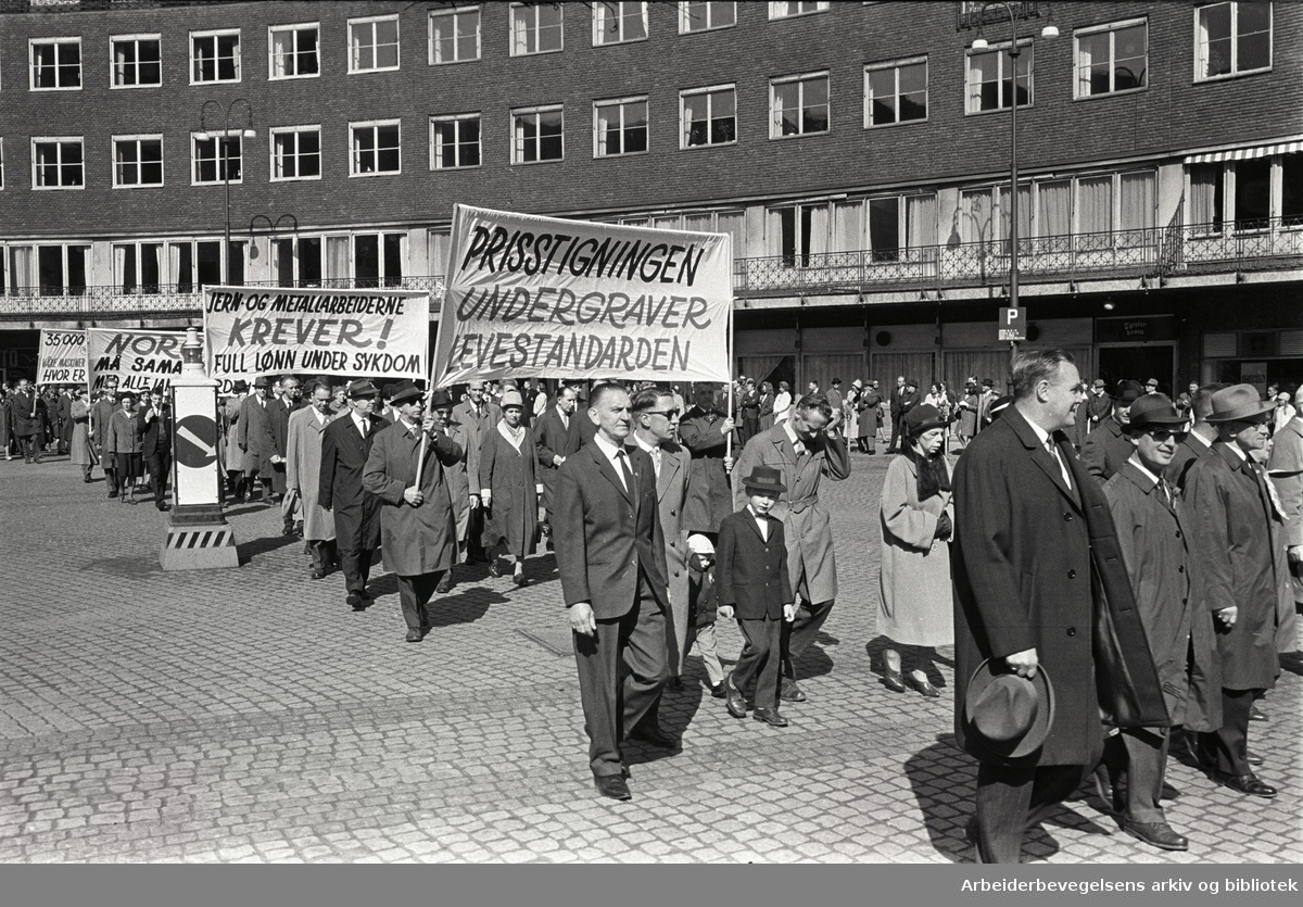 1. mai 1964 i Oslo.Demonstrasjonstoget ved Rådhusplassen.Parole: Prisstigningen undergraver levestandarden.Parole: Jern- og Metallarbeiderne krever! Full lønn under sykdom
