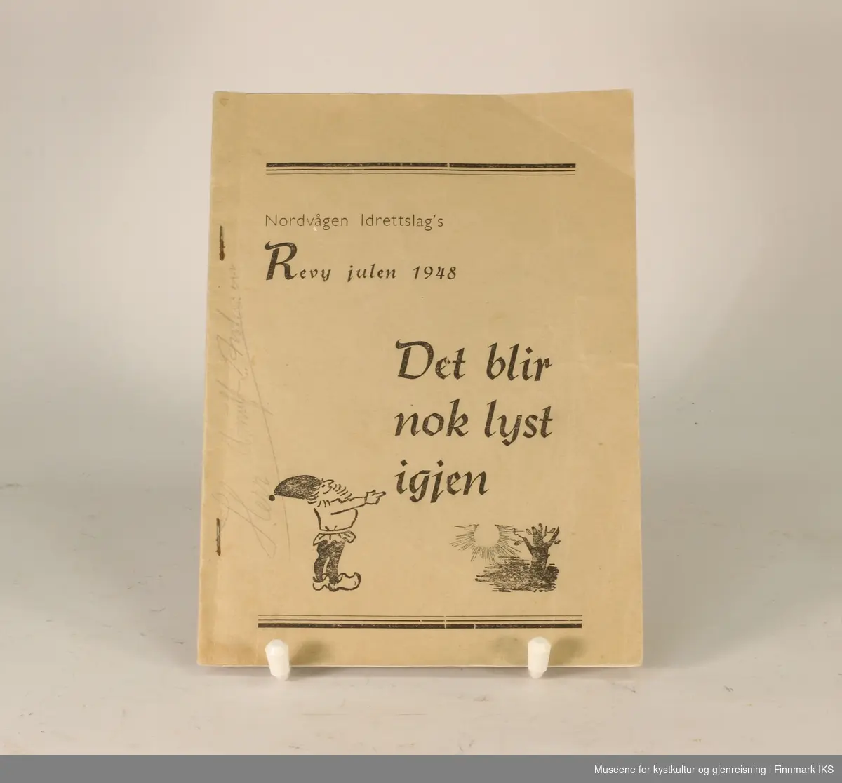 Forsidebilde: Nissefigur med skjegg i tresko, lue og med genser/jakke stukket innenfor beltet. Sol skinner på tre.