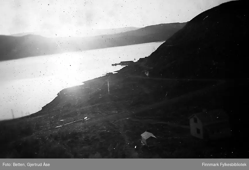 Oversiktsbilde over Smalfjord. Solen går ned bak fjorden. Noen byggninger på forgrunnen
