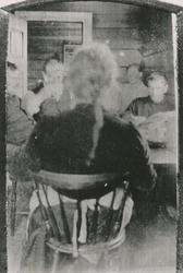 Motiv fra ei stue med flere mennesker rundt et bord. Tatt fr