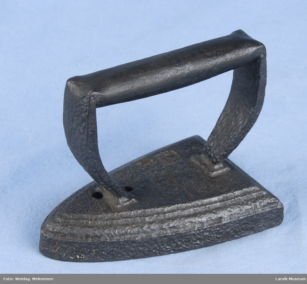 Form: håndtak og stativ i ett, smidd fast til jernet
