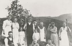 Gruppefotografi av voksne og barn ved en haug med høy. Flere