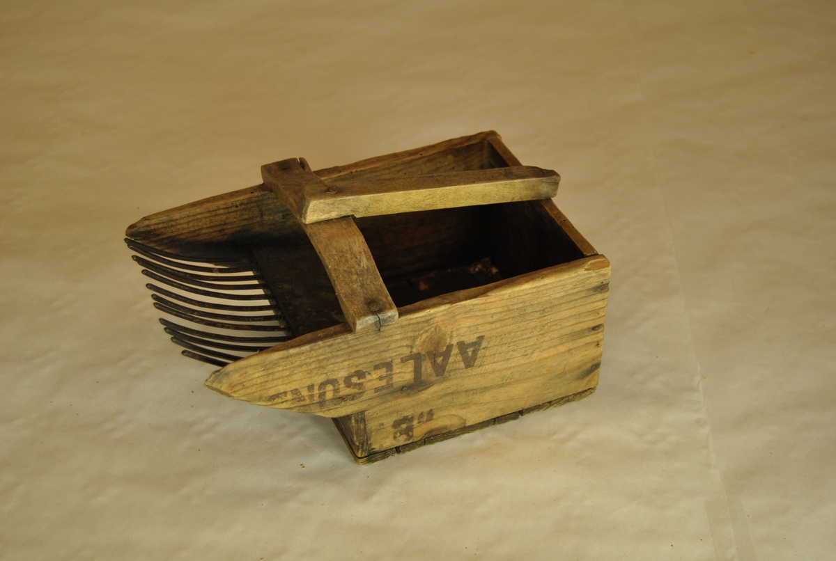 Bærplukker i tre med jerntenner. Med håndtak. Lagd av margarinkasse fra Aalesund.