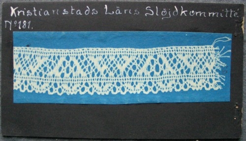 Kristianstads Läns Slöjdkommitté No 181.
Blåkopia på ett spetsprov som är 14 x 3 cm.