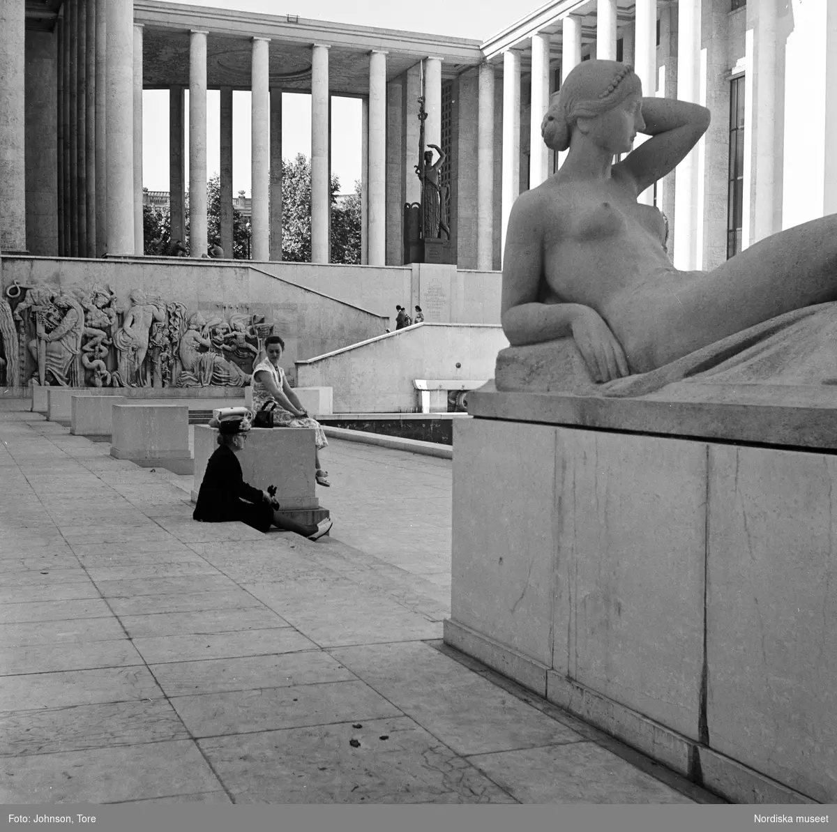Paris. Kolonner och antika statyer på Louvren. En besökare sitter på trappsteg.