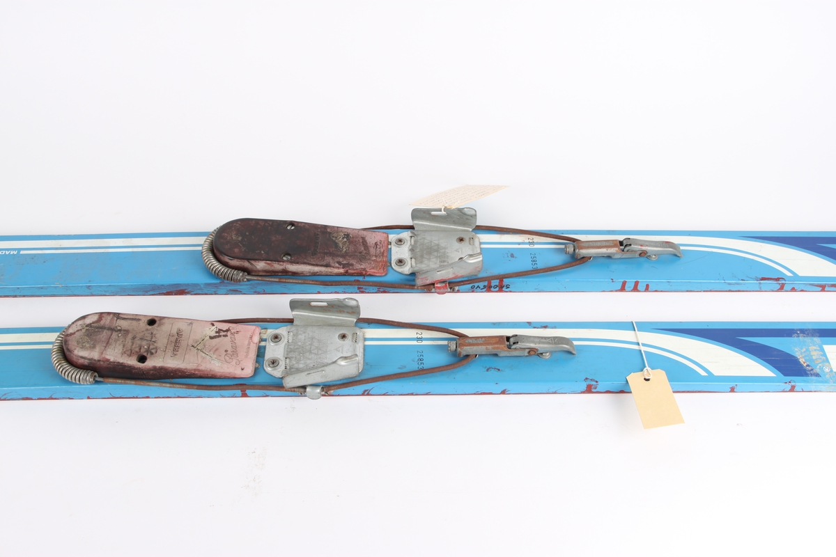 Splitkein hoppski med Kandahar-binding og kloss under støvelen. Skiene er lakkert under for bruk på plast om sommeren.