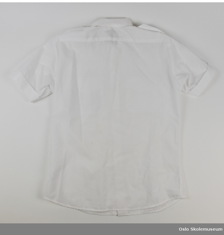 Hvit skjorte fra Lambertseter skoles musikkorps til barn. Skjorten har korpsets emblem.