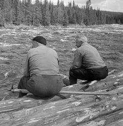 To arbeidskledde tømmerfløtere, fotografert mens de kvilte p