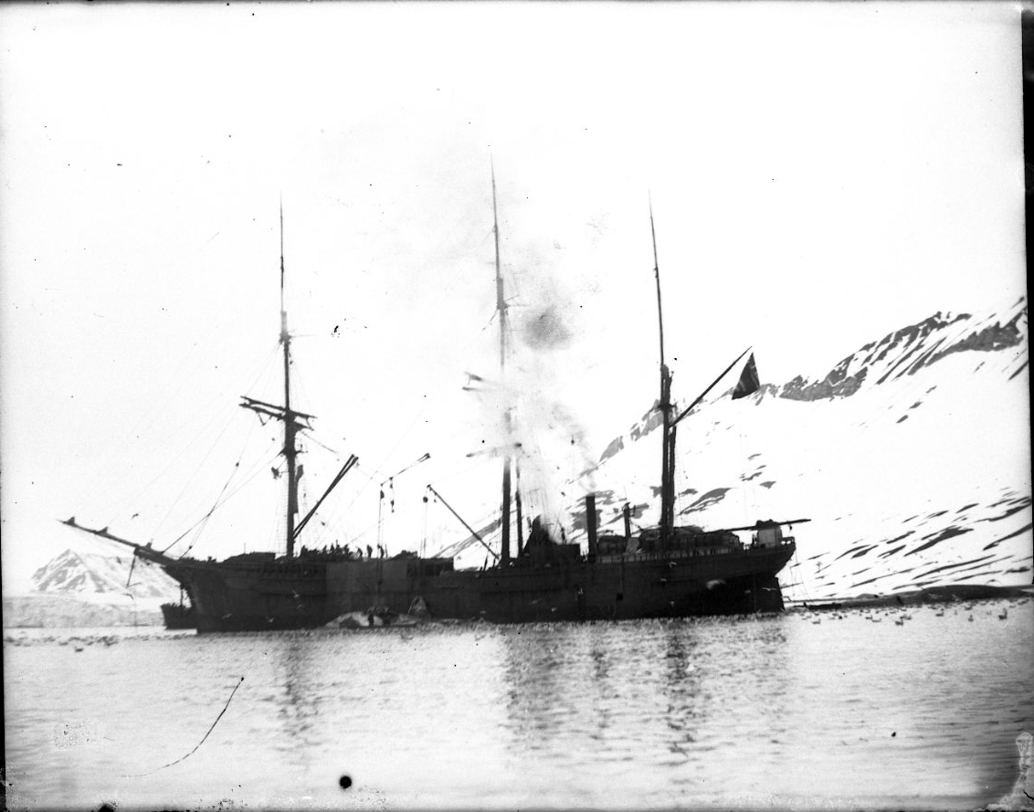 Ett oidentifierat troligen norskt tremastat ångfartyg för ankar vid Spetsbergen. Det ryker möjligen från skorstenen. Snöklädda berg i bakgrunden.