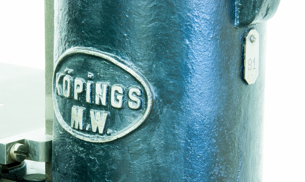 Fyrspindlig borrmaskin. Etikett, text: "Fyrspindlig borrmaskin 1869". Skylt med "Köpings M W" samt liten bricka med "91".