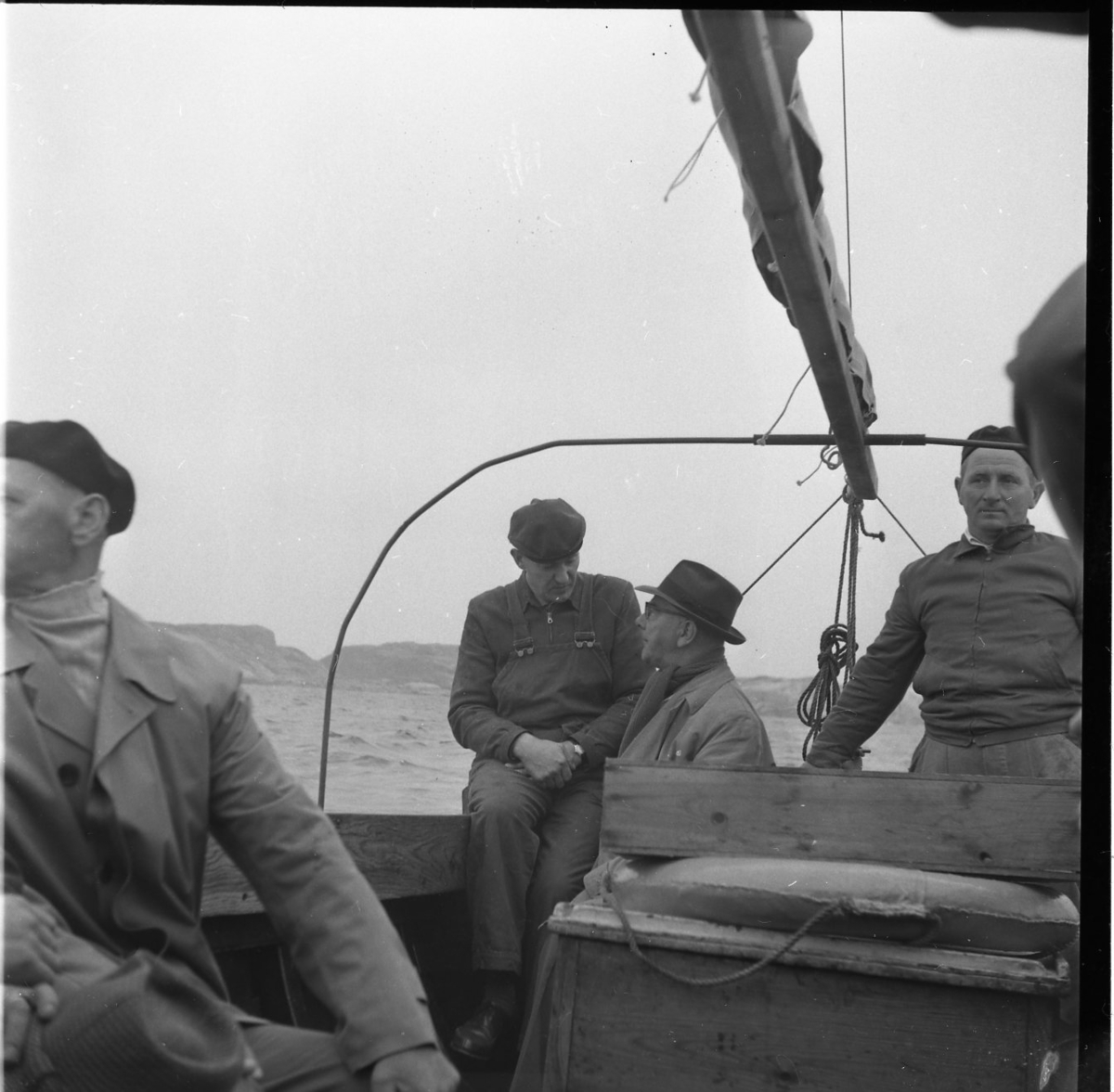 Fyra män i en segelbåt med inombordare. Mannen i hatt och ljus rock i aktern är troligen Osse Gustafsson.