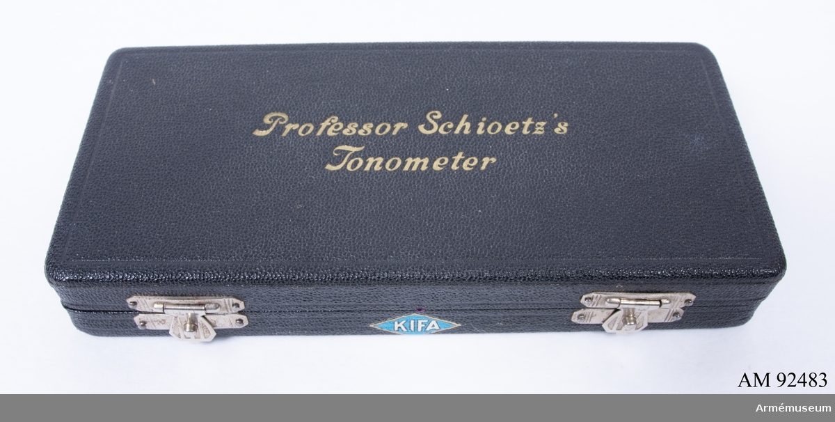Svart etui märkt Professor Schioetz´s Tonometer på locket samt KIFA på botten. Etuits insida är klädd med lila tyg och innehåller en tonometer för mätning av förändring av ögontryck. Tonometern märkt: 9226.