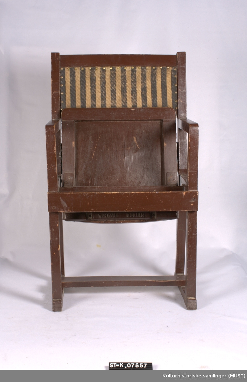 Klappstol, brunmalt. Setet har sekundært trekk av voksduk. Ryggen har stripet trekk med pyntenagler.
Stol med ermlener, stofftrukket rygg i brunt og svartstripet stoff. Klappsetet trukket med rød-hvit og blårutet plastduk. Setet hengslet på en tverrgående stokk i stolen. Klappstolen har vært en i en rekke (i hvert fall satt sammen to og to).