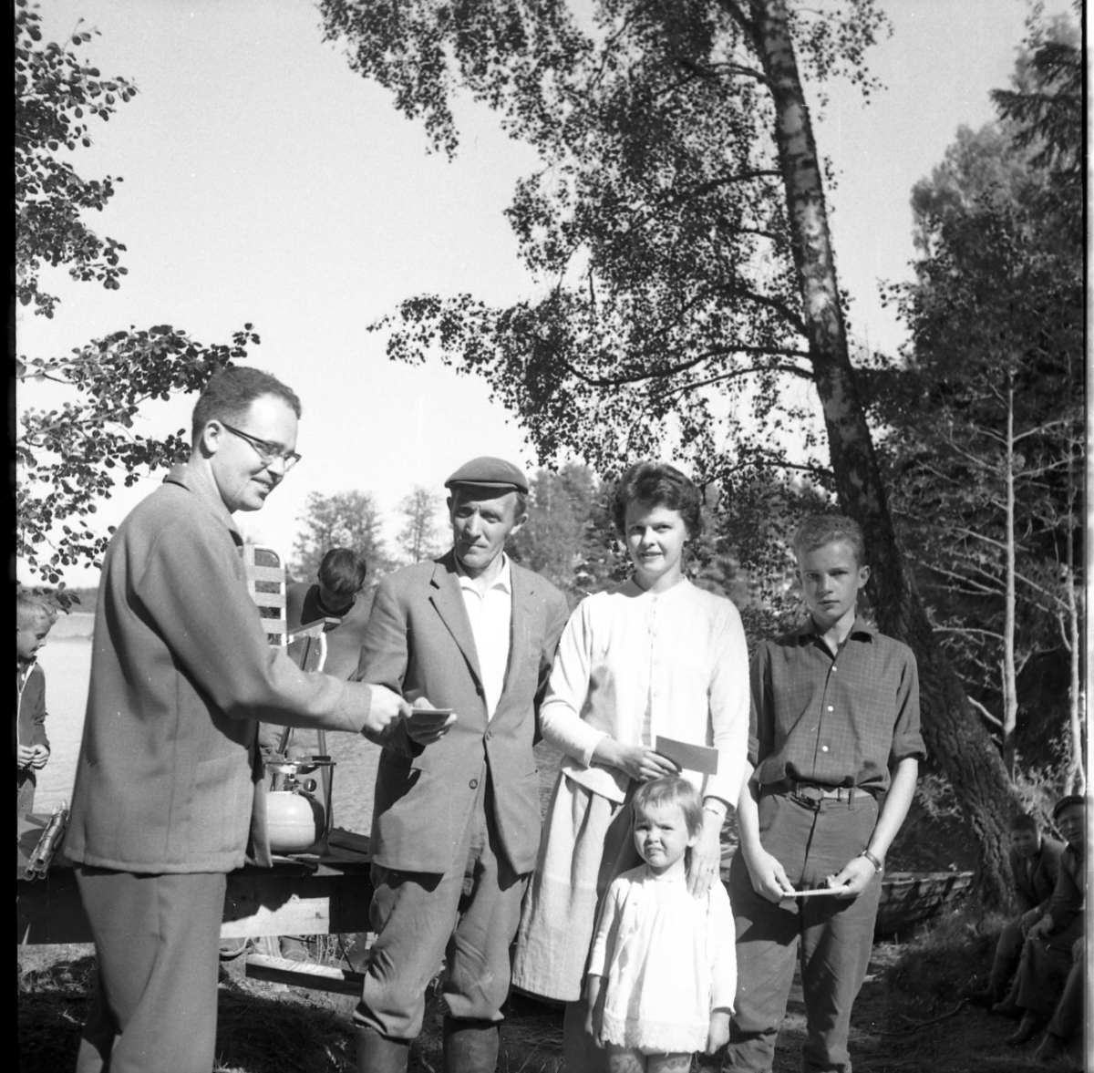 En man med glasögon delar ut priser? till en man, en kvinna med en liten flicka samt en pojke. De är från vänster Ingemar Lago, Ivar Adolfsson och Birgitta Berglund.