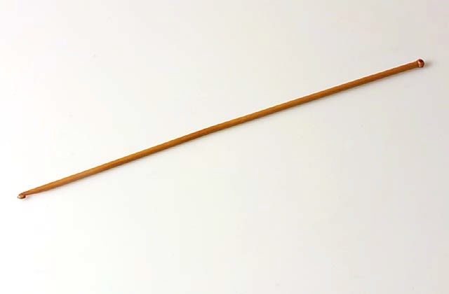 En krokningsnål av brunt trä.krokningsålen kommer från Hultmans Broderiaffär, som låg på Borgmästaregatan fram till 1966.