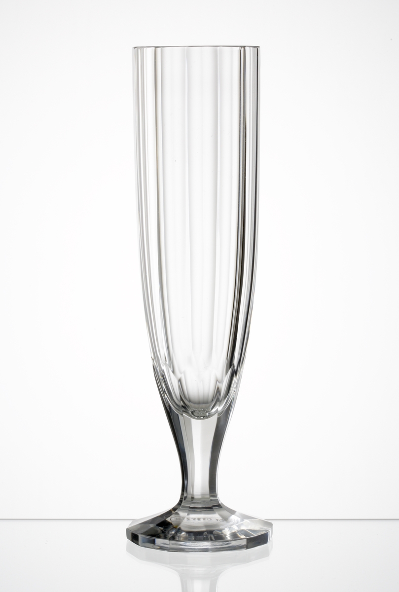 Design: Edward Hald, Orrefors. 
Champagneglas. Tolv stående facetter runt kupan. Facetterna fortsätter längs benet och ut på foten. 
Vit etikett: HA 3104.