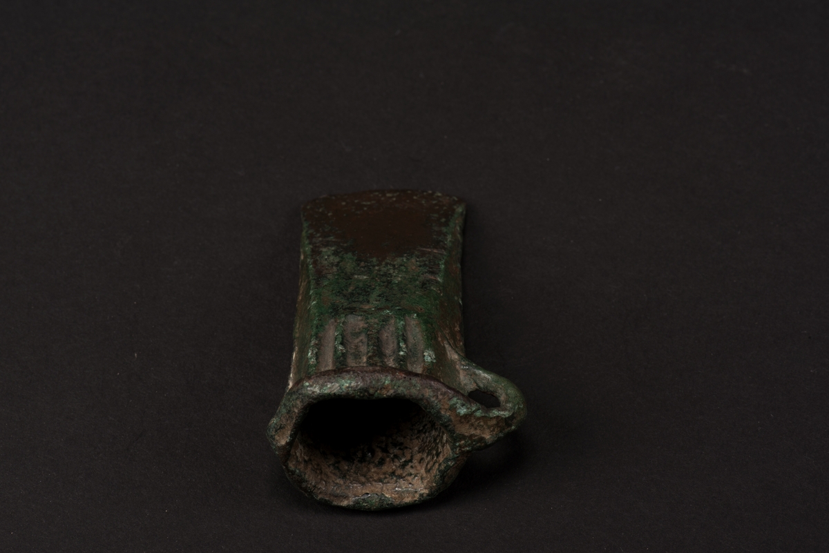 Holkyxa av brons med tre vertikala ränder under mynningen.