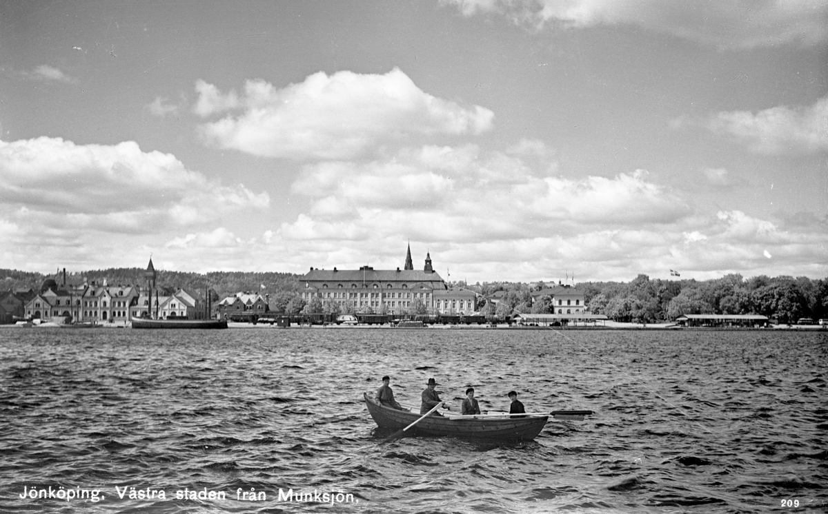 Västra delen av Jönköping sedd från Munksjön. I förgrunden en eka med fyra män som ror på sjön.