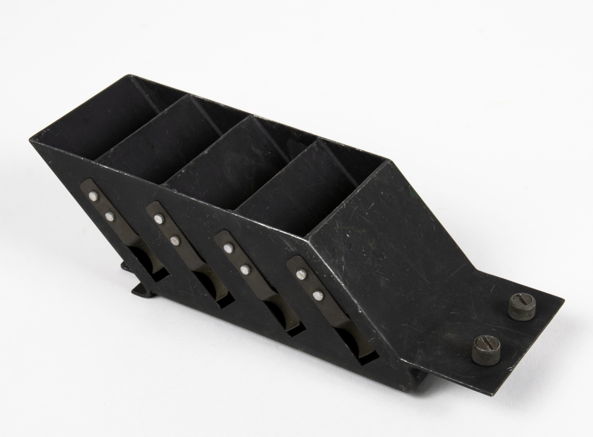 Kasetthållare för registerkamera 14 i svart lättmetall, innehåller fyra fack för kasetter. Påskrifter på undersidan.